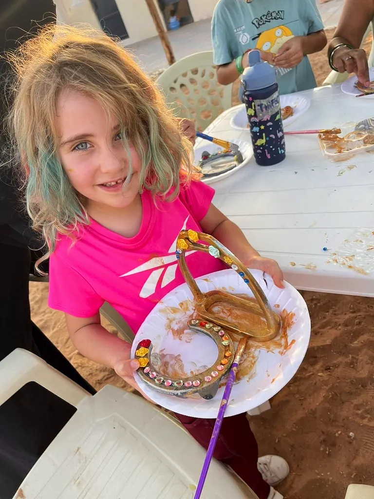 Young girl proudly showing her decorated horseshoe at the art and craft activity during the Spring Kids Camp at Al Jazeerah Equestrian Club in Ras Al Khaimah