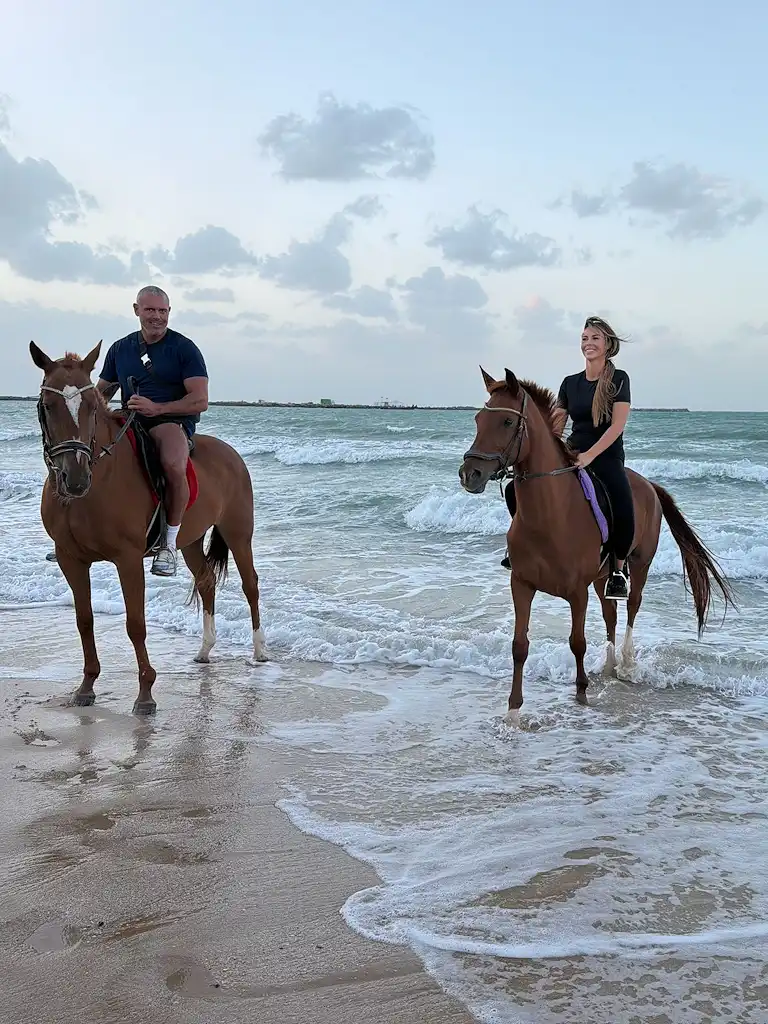 Couple enjoying a sunset beach horse riding experience in Ras Al Khaimah, one of the top outdoor and romantic activities to do in RAK near Marjan Island.
